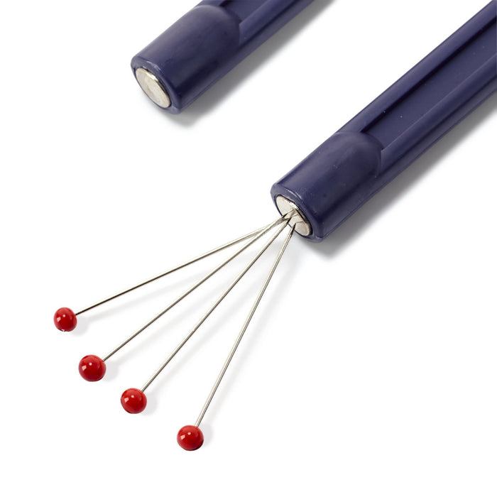 Purple needle holder with red pins on a white background