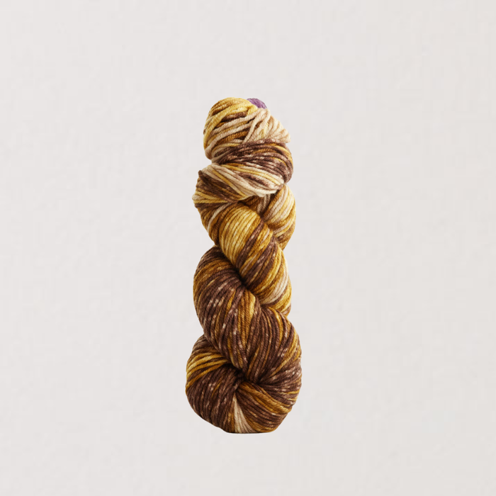 Braided skein of yarn in brown, yellow, and beige on a light gray background