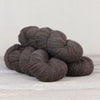 Dark brown yarn skeins on a light wooden surface with a white background