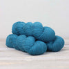 Blue yarn skeins on a light wooden surface with a white background