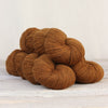 Brown yarn skeins on a light wooden surface with a neutral background