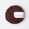 Ball of dark red yarn with 'Knitting for Olive' label on a white background
