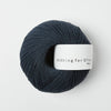 Ball of dark blue yarn with a label on a white background