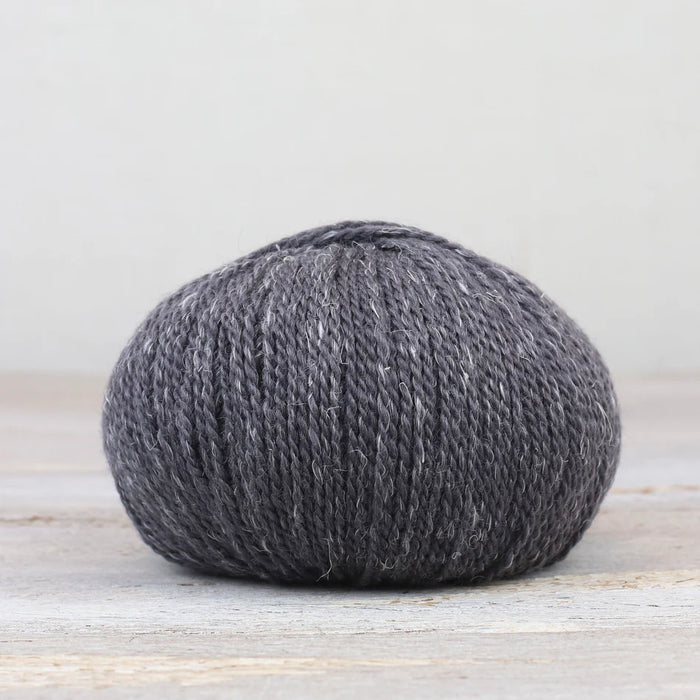 Ball of gray yarn on a light wooden surface