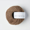 Ball of brown yarn with a 'Knitting for Olive' label on a white background