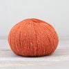Orange skein of yarn on a light wooden surface