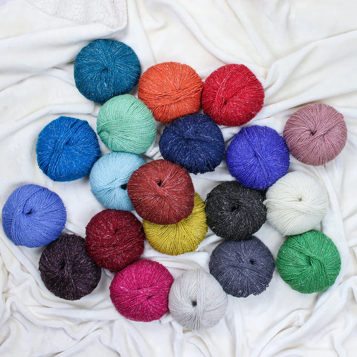Assorted colorful yarn balls on a white fabric background