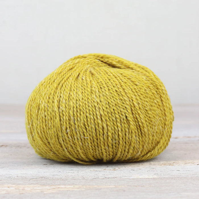 Yellow skein of yarn on a light wooden surface