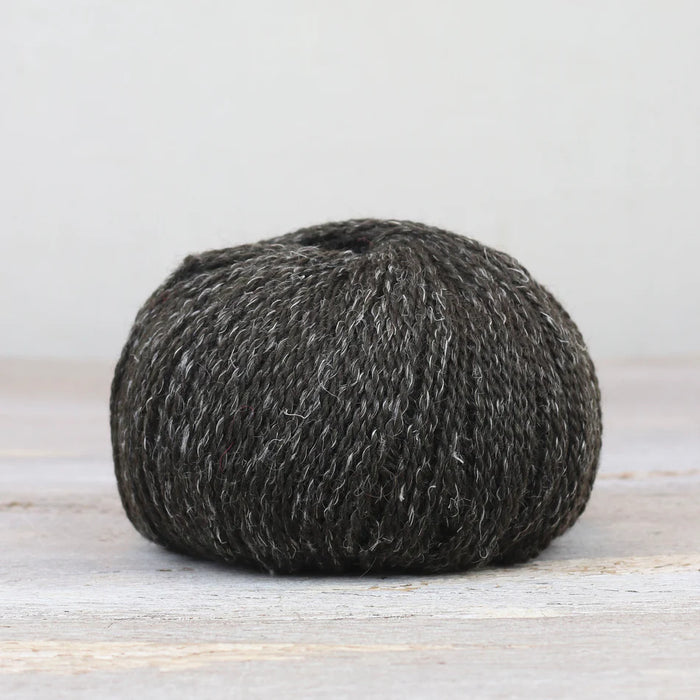 Ball of dark gray yarn on a light wooden surface