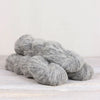 Gray yarn skeins on a light wooden surface with a white background