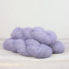 Purple yarn skeins on a light wooden surface with a white background