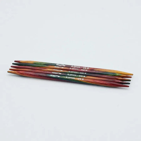 Set of colorful knitting needles on a light gray background