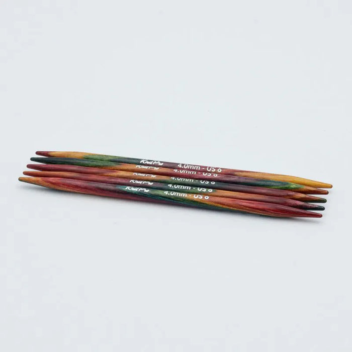 Set of colorful knitting needles on a light gray background