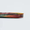Set of wooden knitting needles with size markings on a light gray background