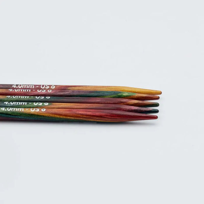 Set of wooden knitting needles with size markings on a light gray background