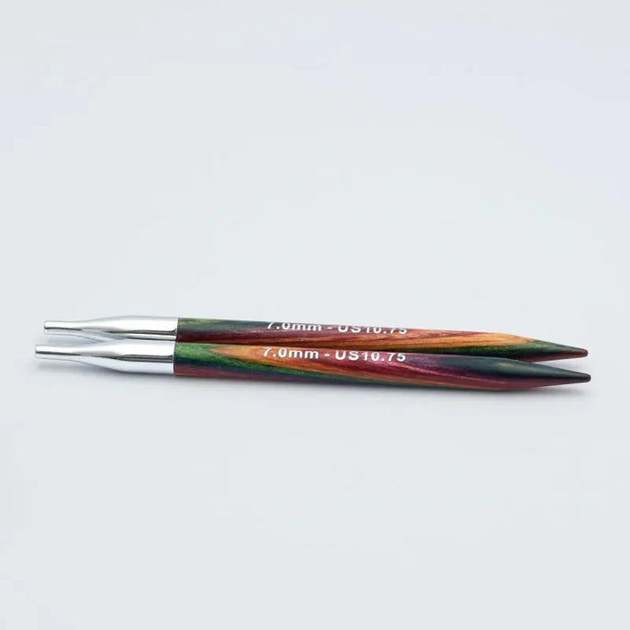 Two 7.0mm circular knitting needles with metallic silver tips and colorful marbled handles in green, orange, and red, shown on a light gray background.