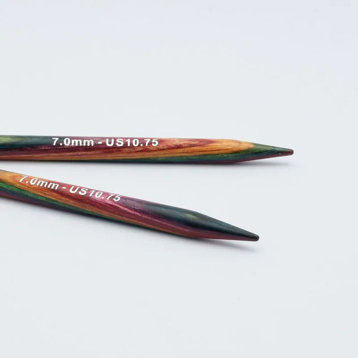 Two wooden knitting needles with a rainbow marbled finish and white printed text reading '7.0mm - US10.