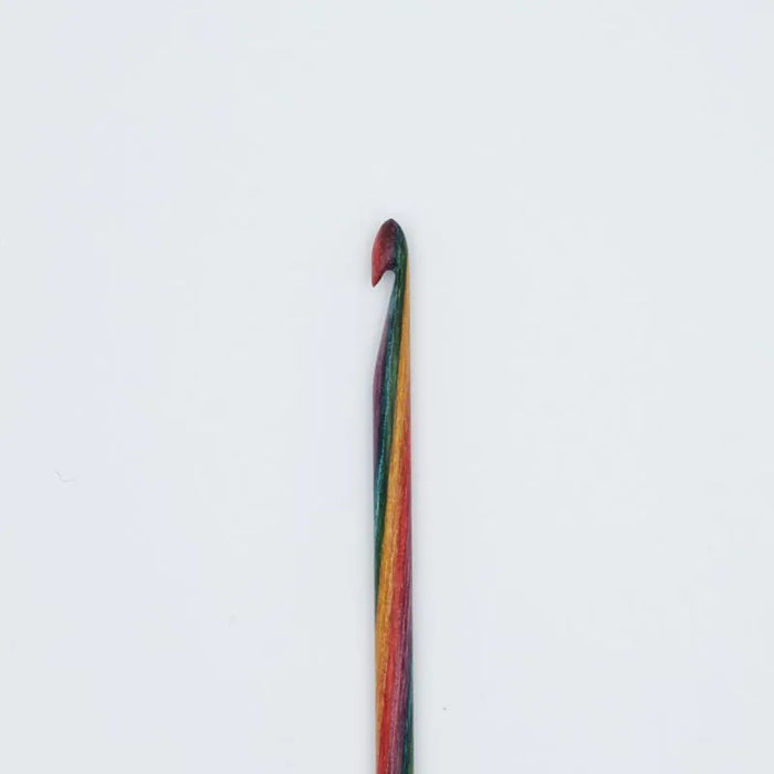 A single crochet hook with a multicolored striped handle, featuring red, orange, yellow, green, and blue stripes, set against a plain white background.