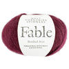 Ball of burgundy yarn with West Yorkshire Spinners Fable label on a white background