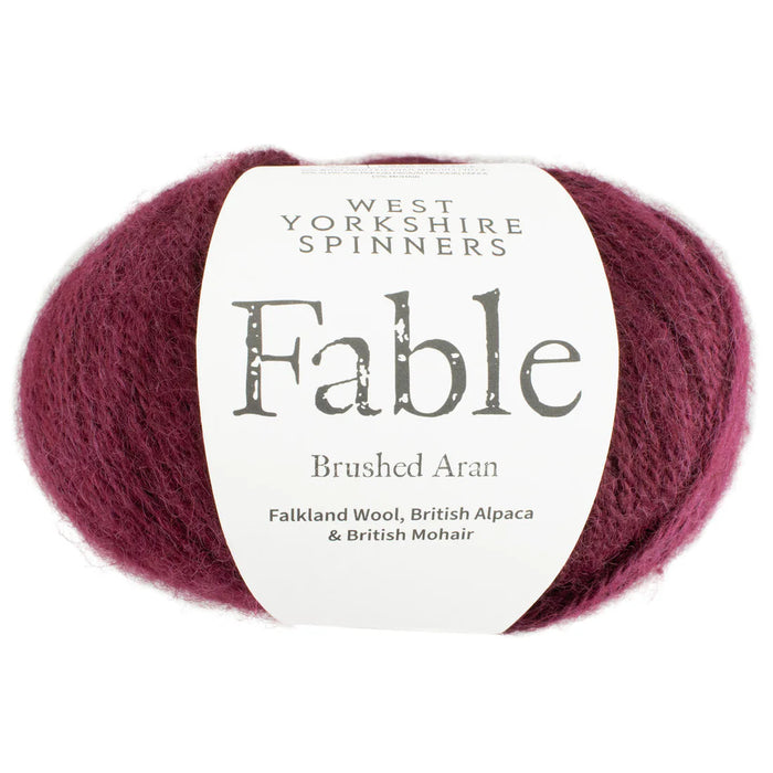Ball of burgundy yarn with West Yorkshire Spinners Fable label on a white background